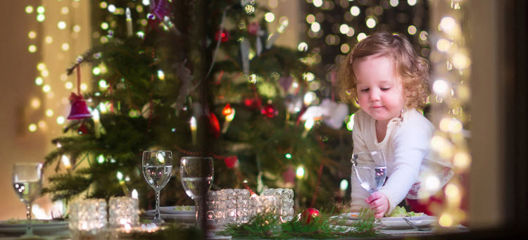 small girl playing with christmas decorations in front of red and purple decorated christmas tree