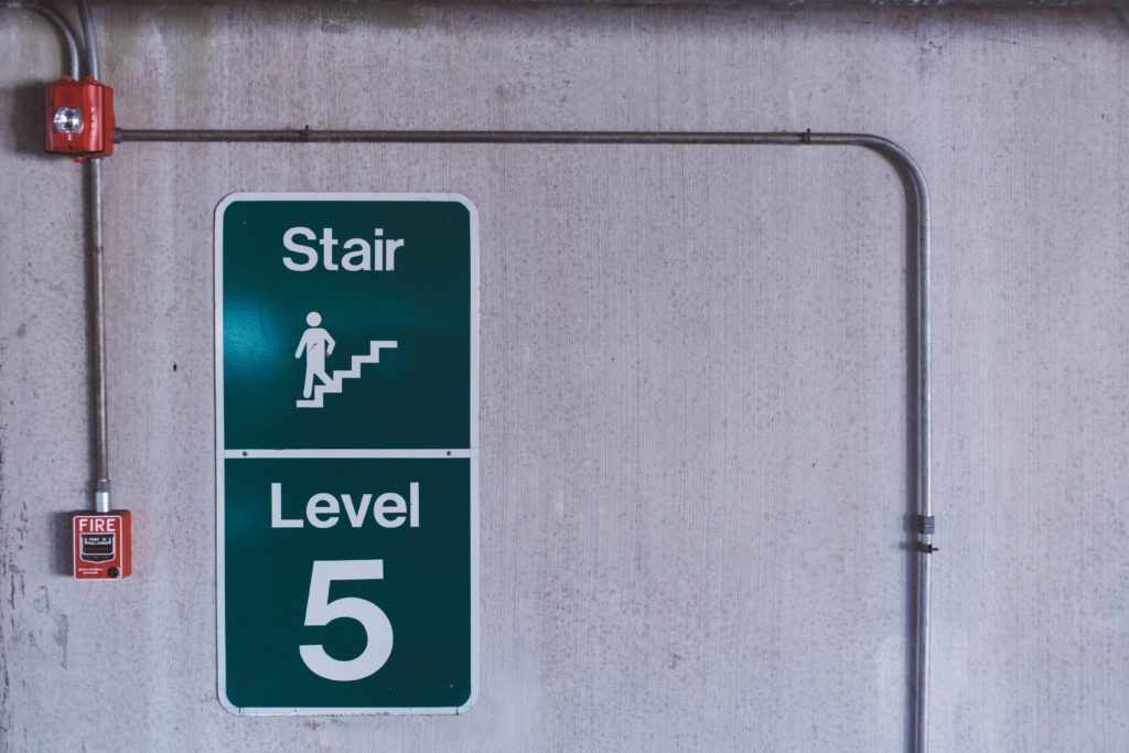 View of fire alarm in parking garage next to stair level 5 sign.